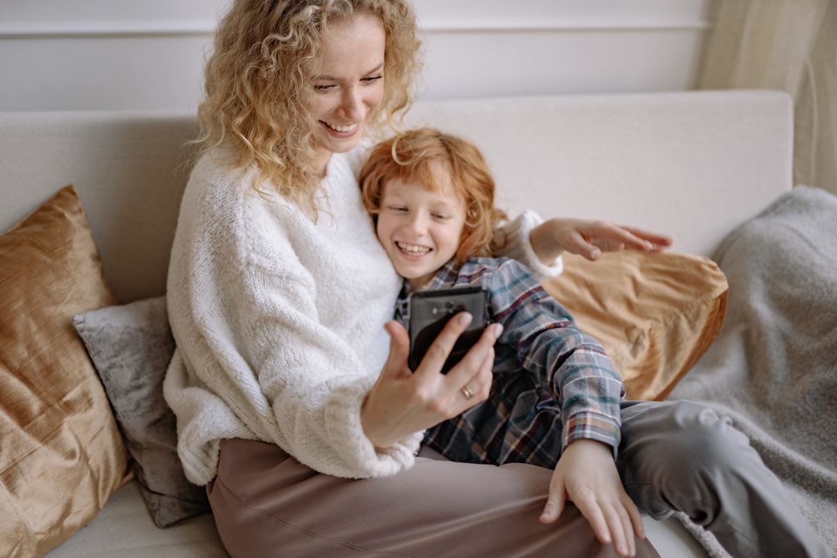 Photo of a woman and child smiling and looking at a cell phone