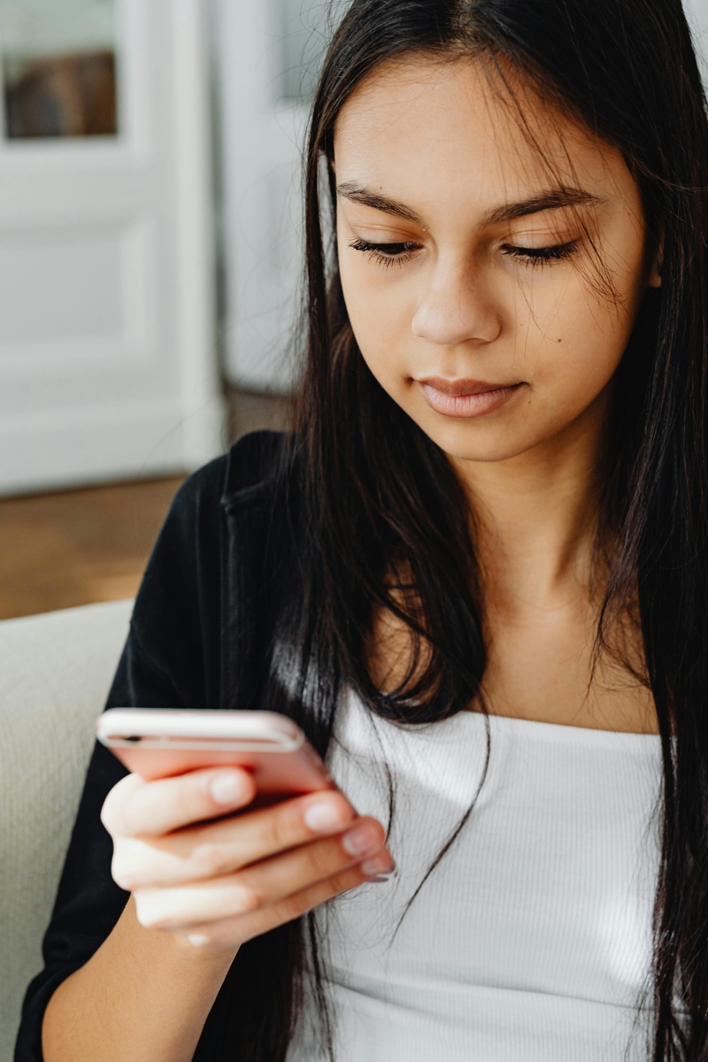 A girl looks at a cell phone.