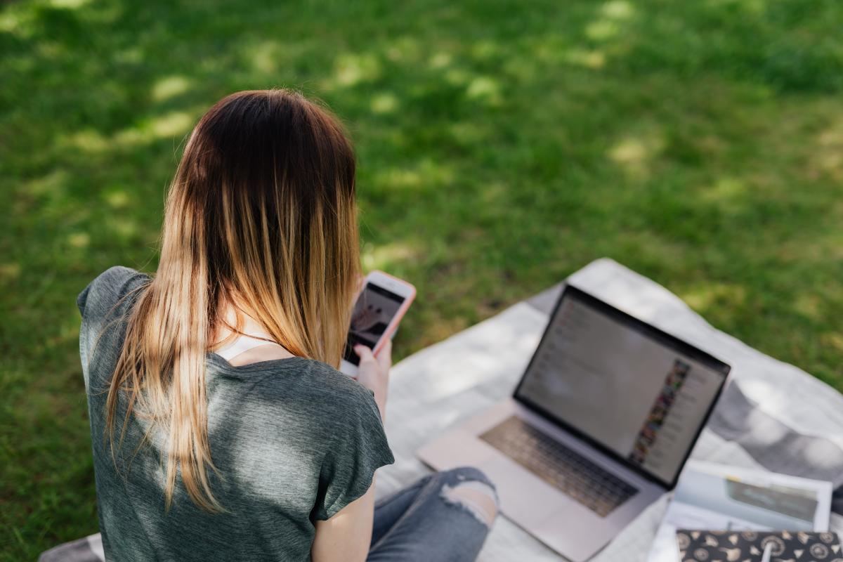 Woman with laptop looking at cell phone