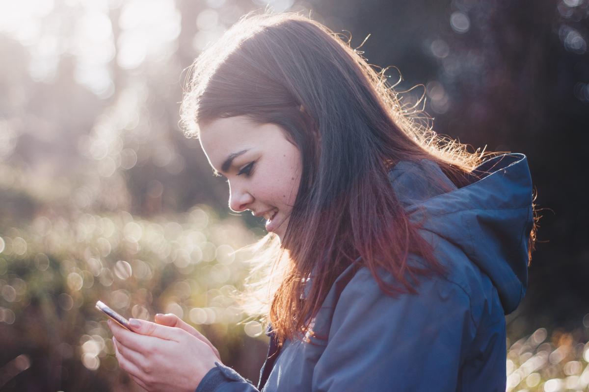 Teen girl looking at cell phone and smiling