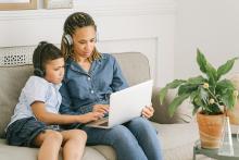 A woman and child sit and look at a laptop together.